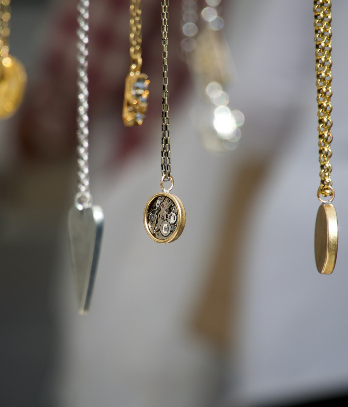 Colares com pingentes de ouro e prata pendurados no ateliê