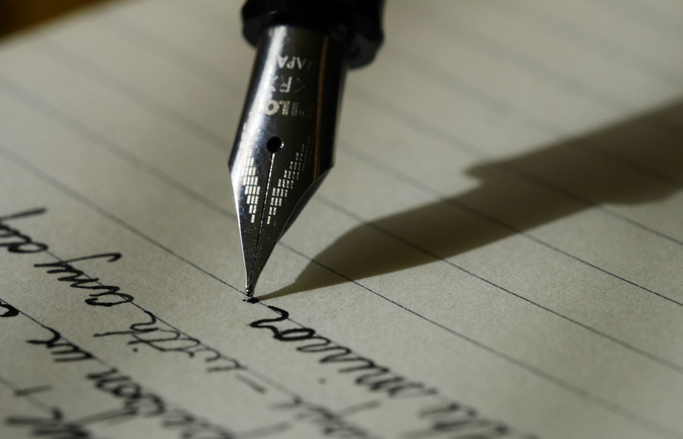Caneta-tinteiro escrevendo em um caderno pautado