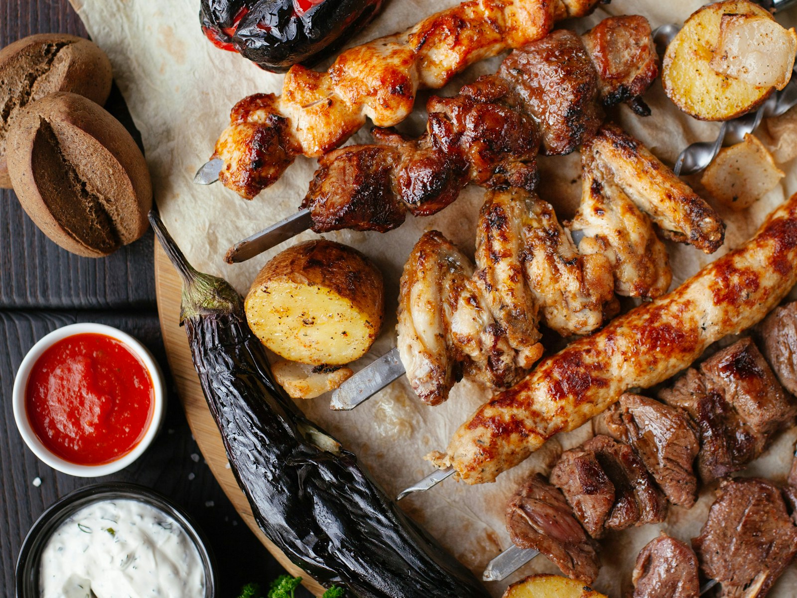 Tábua com carnes na brasa, legumes assados e molhos